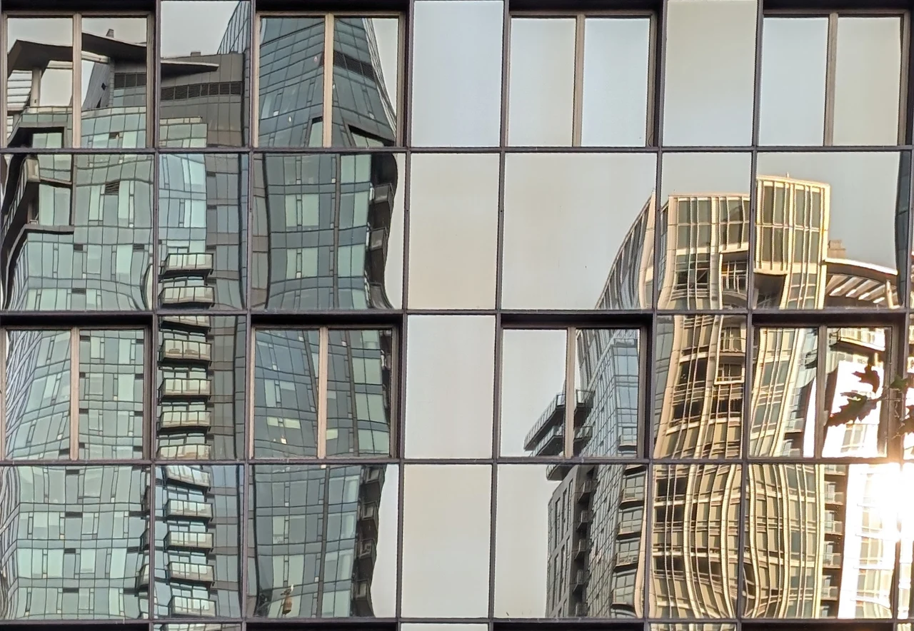Warm buildings reflected in a grid of steel-framed windows.