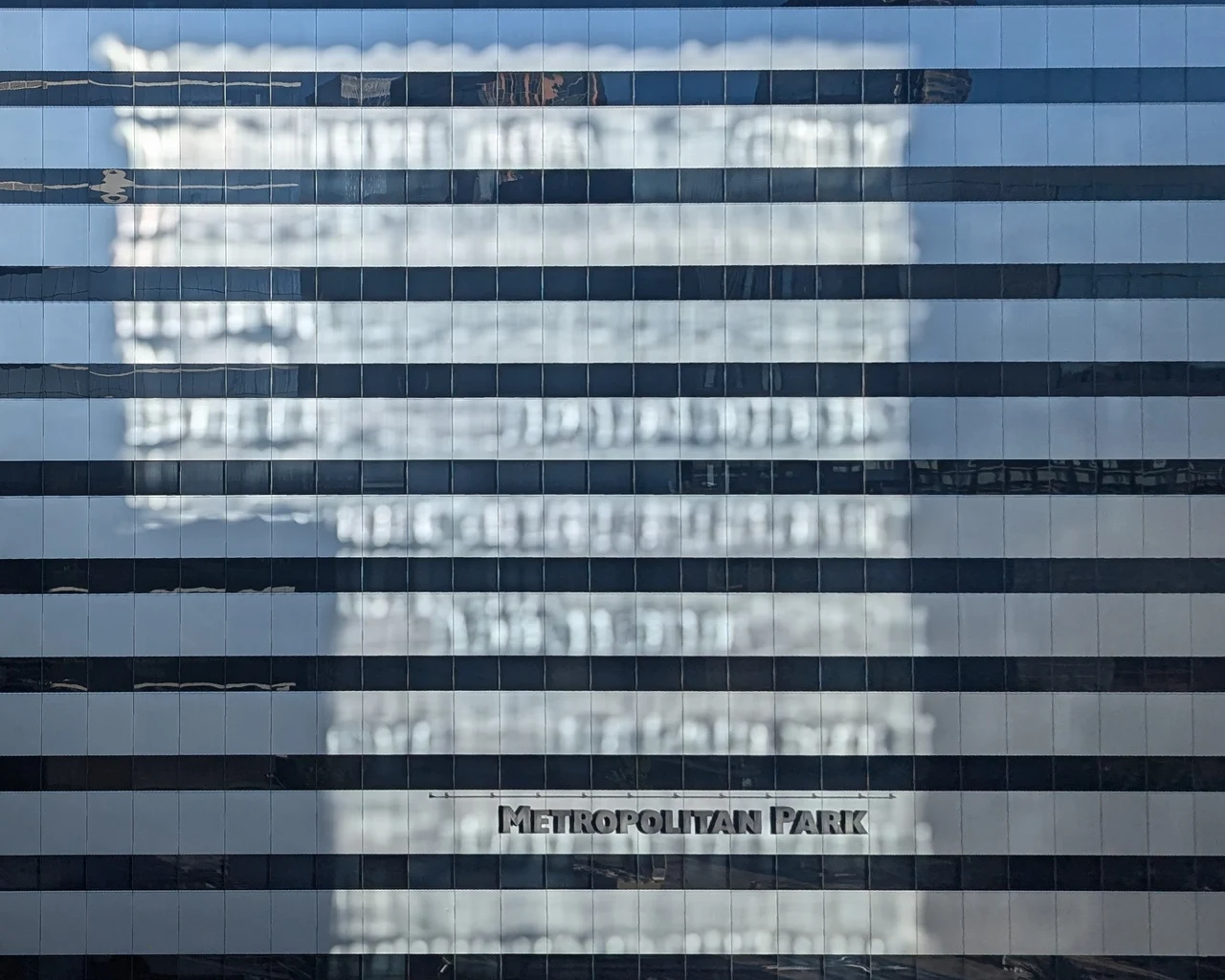 A pale building rippling across horizontal bands of glass.