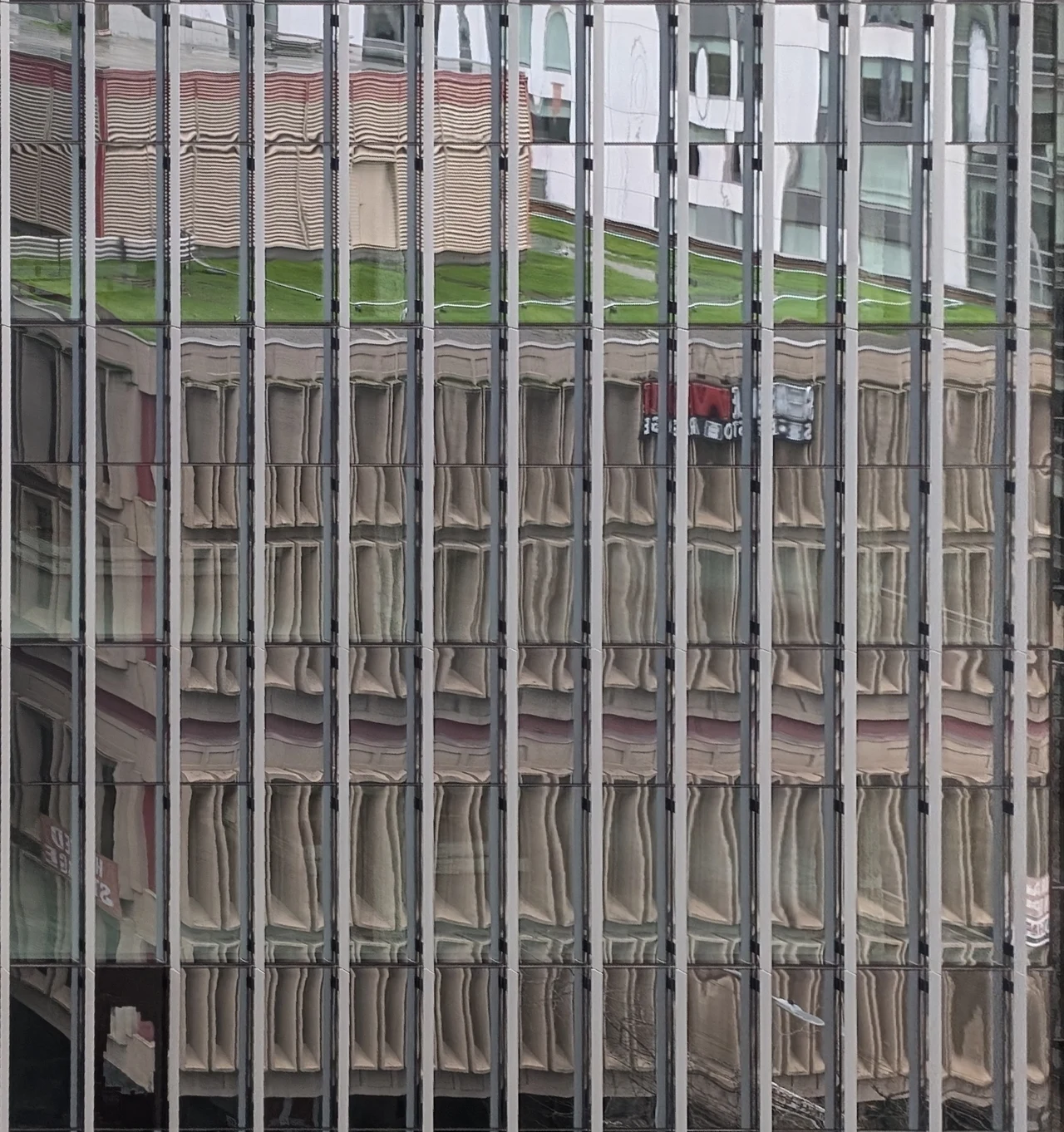 Repeated silver mullions stretching a reflected facade.
