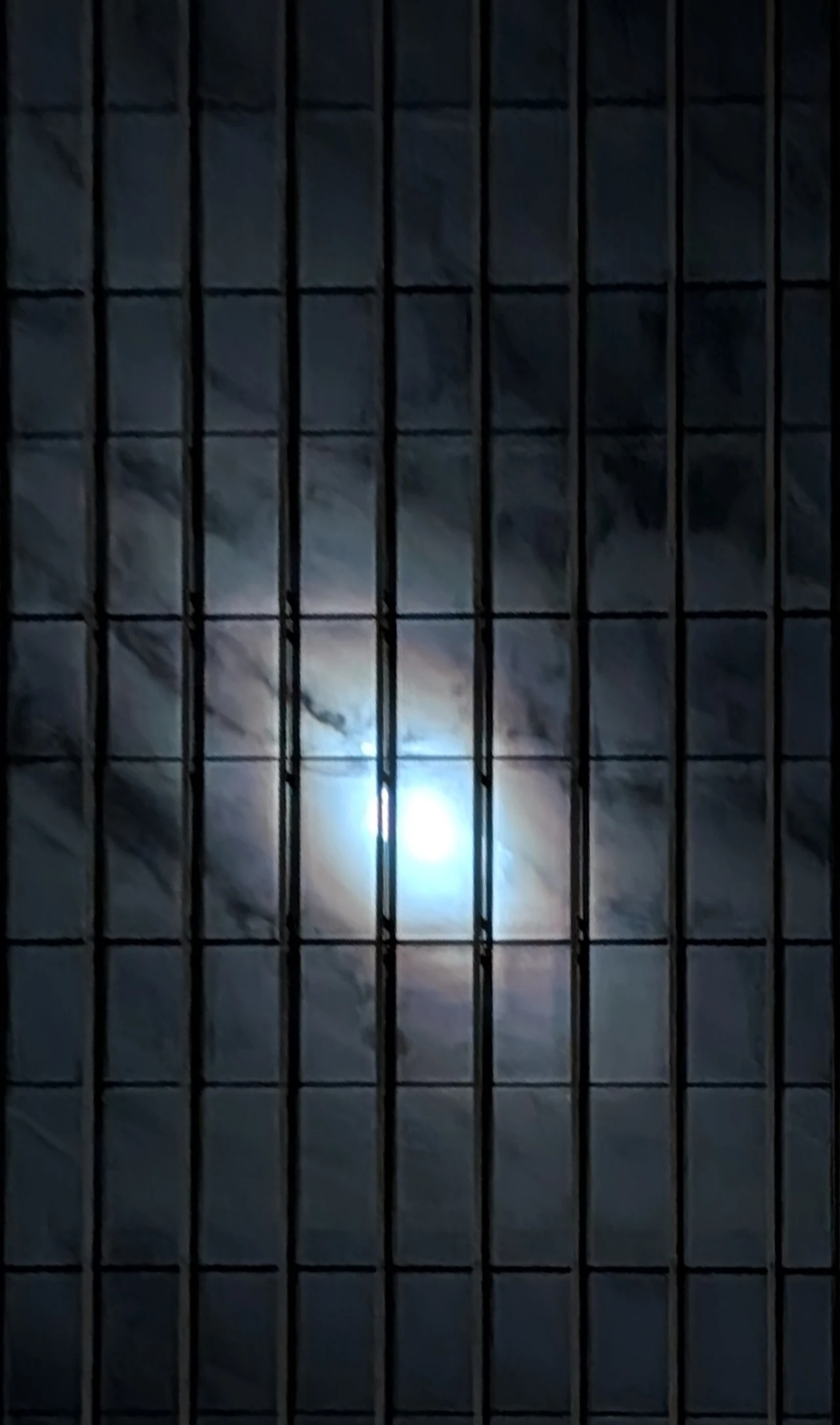 A small burst of sunlight in a dark blue glass facade.