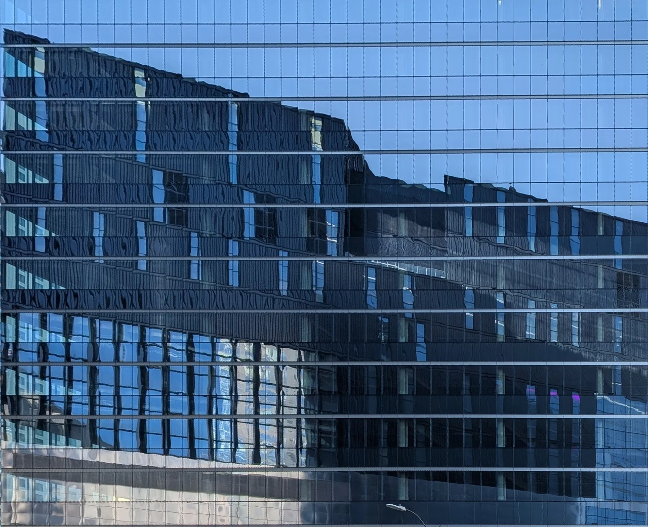Layers of blue buildings reflected across horizontal window lines.