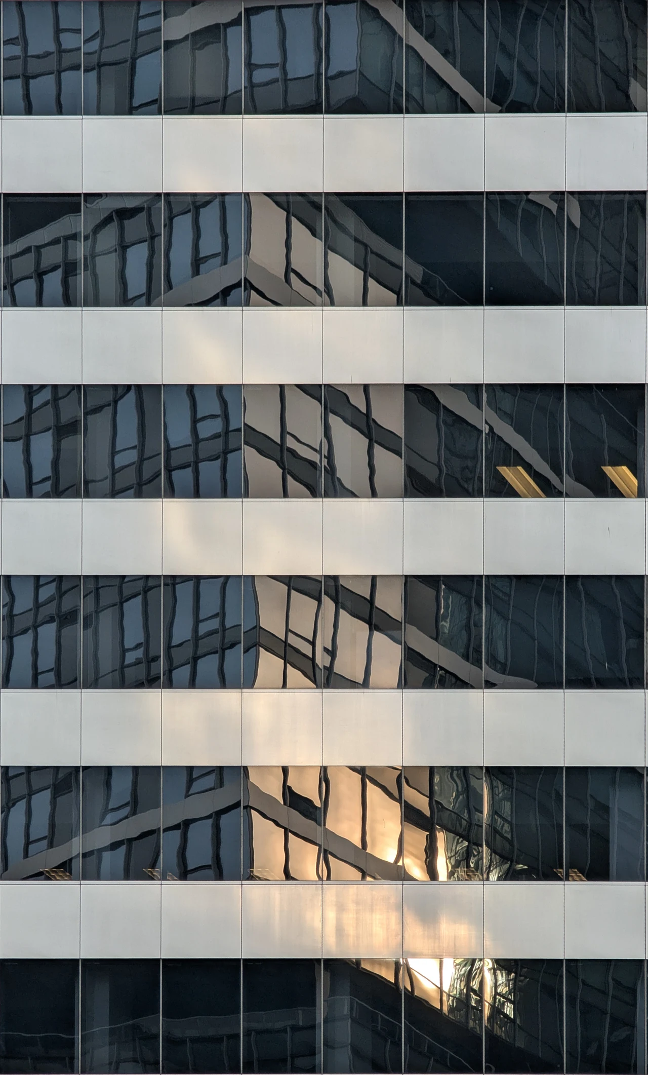 Broad pale bands crossing a reflective tower in warm light.