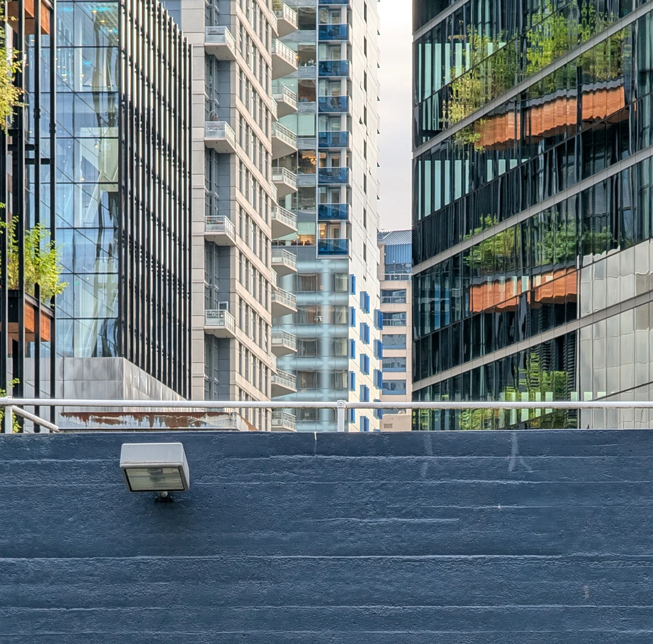 Overlapping apartment facades reflected above a blue wall.