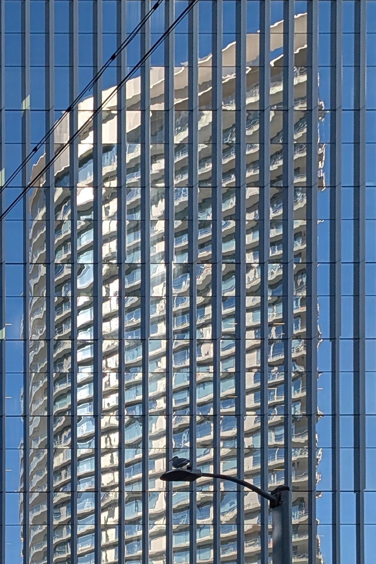 A pale building reflected in tall blue window grids.